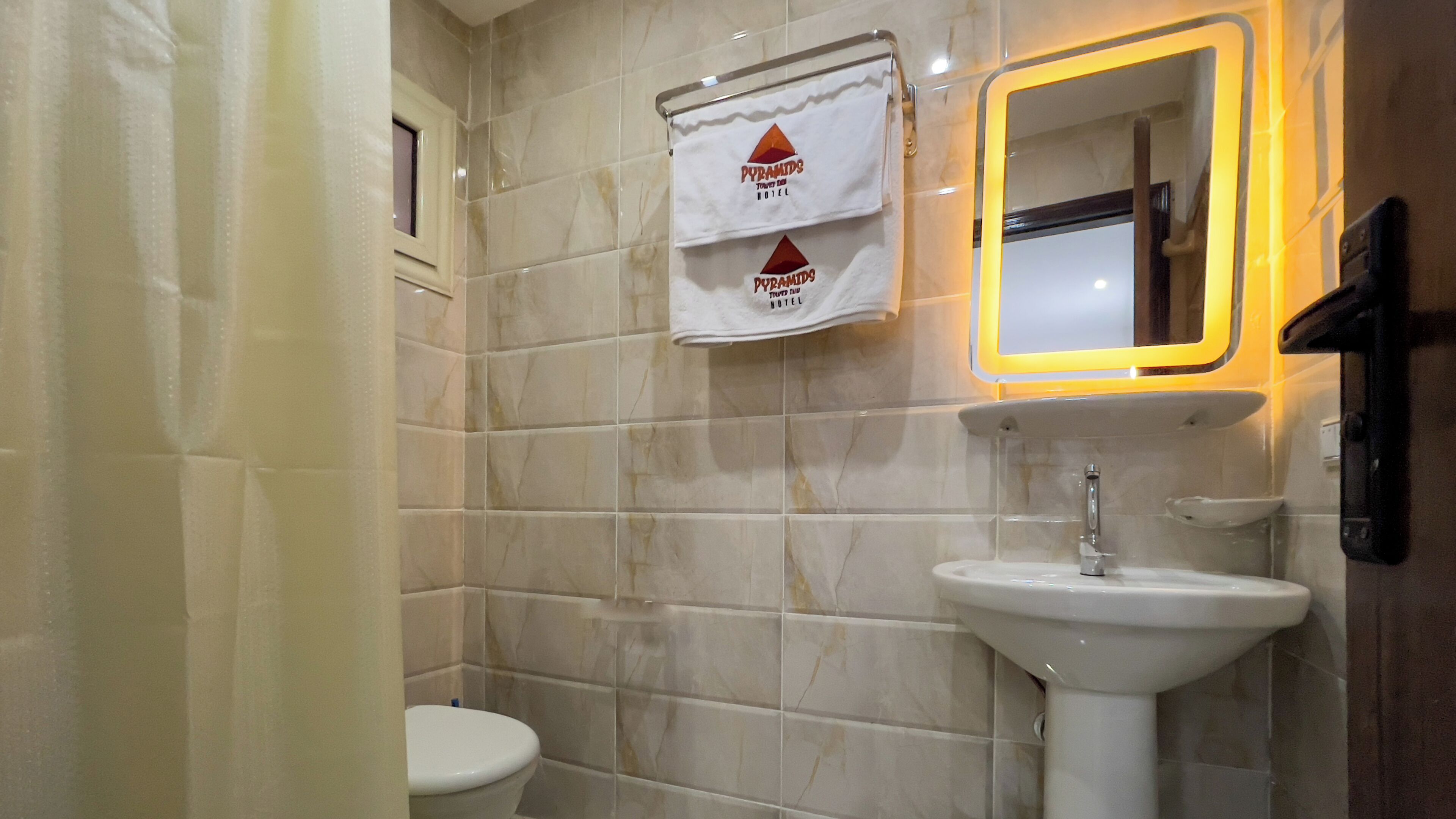 A bathroom with a white sink, a mirror with a yellow frame, and a towel rack with two towels.