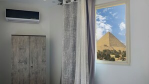 A room with a view of a pyramid, a wooden door, and a television on the wall. - pyramids tower view inn (Giza)