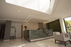 A reception desk with a marble top, a modern light fixture, and a view of the outdoors.