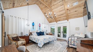 Un dormitorio amplio con una cama grande, techo de madera y vistas al exterior.