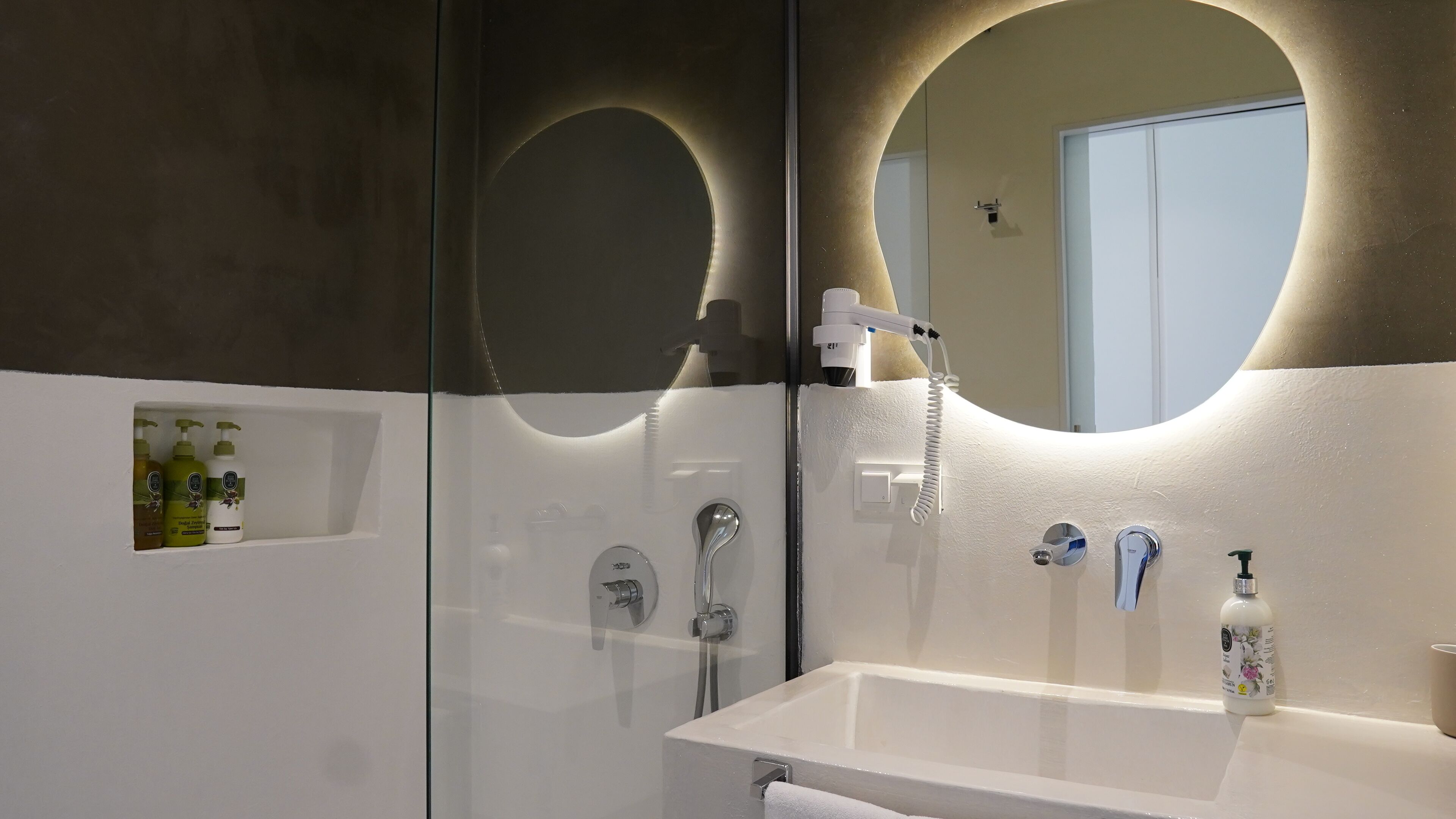 A modern bathroom with a glass shower enclosure, a white sink with a mirror, and a towel rack.