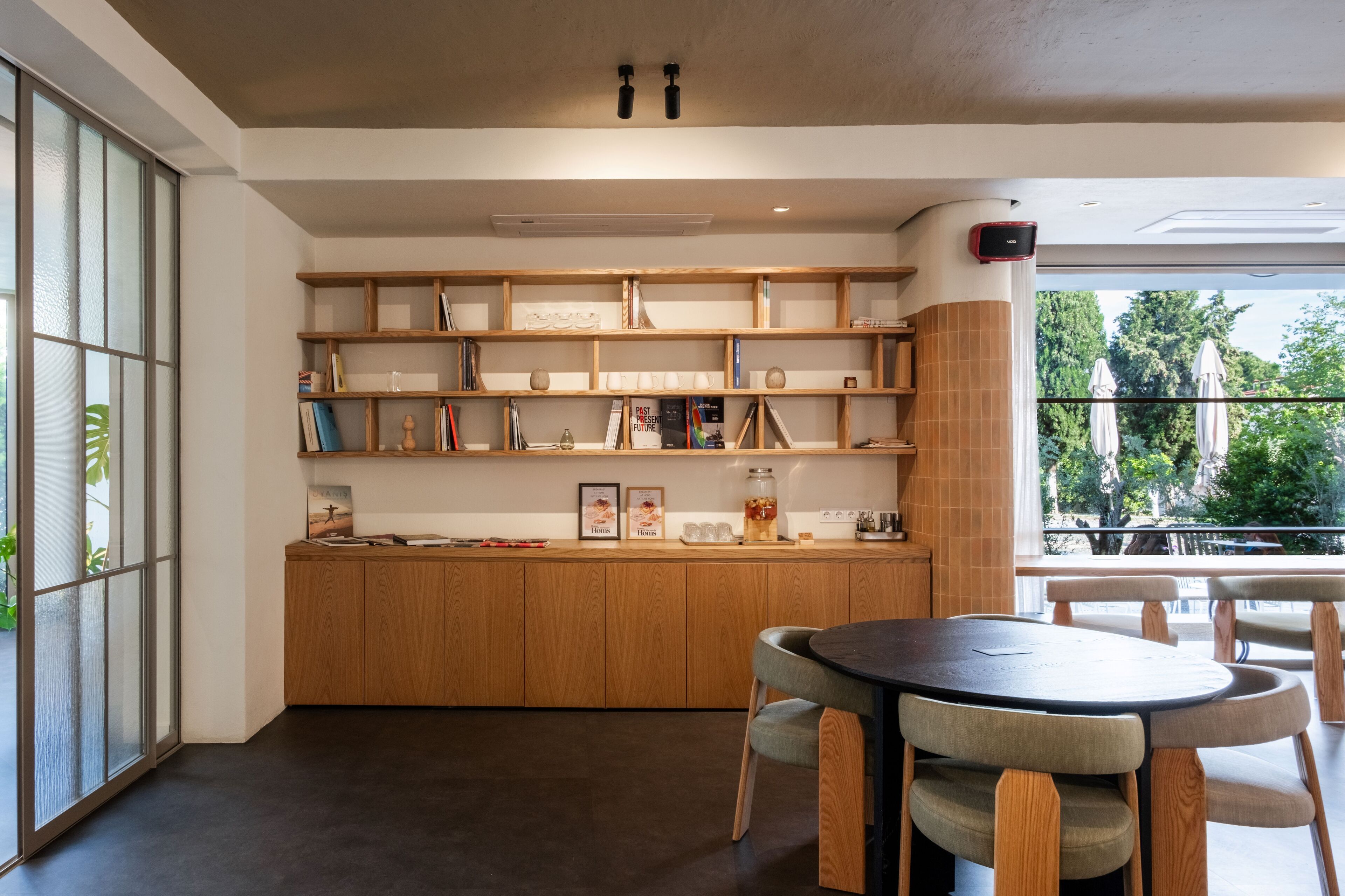 Une cuisine moderne avec des meubles en bois, une table de salle à manger ronde et une vue sur l’extérieur.