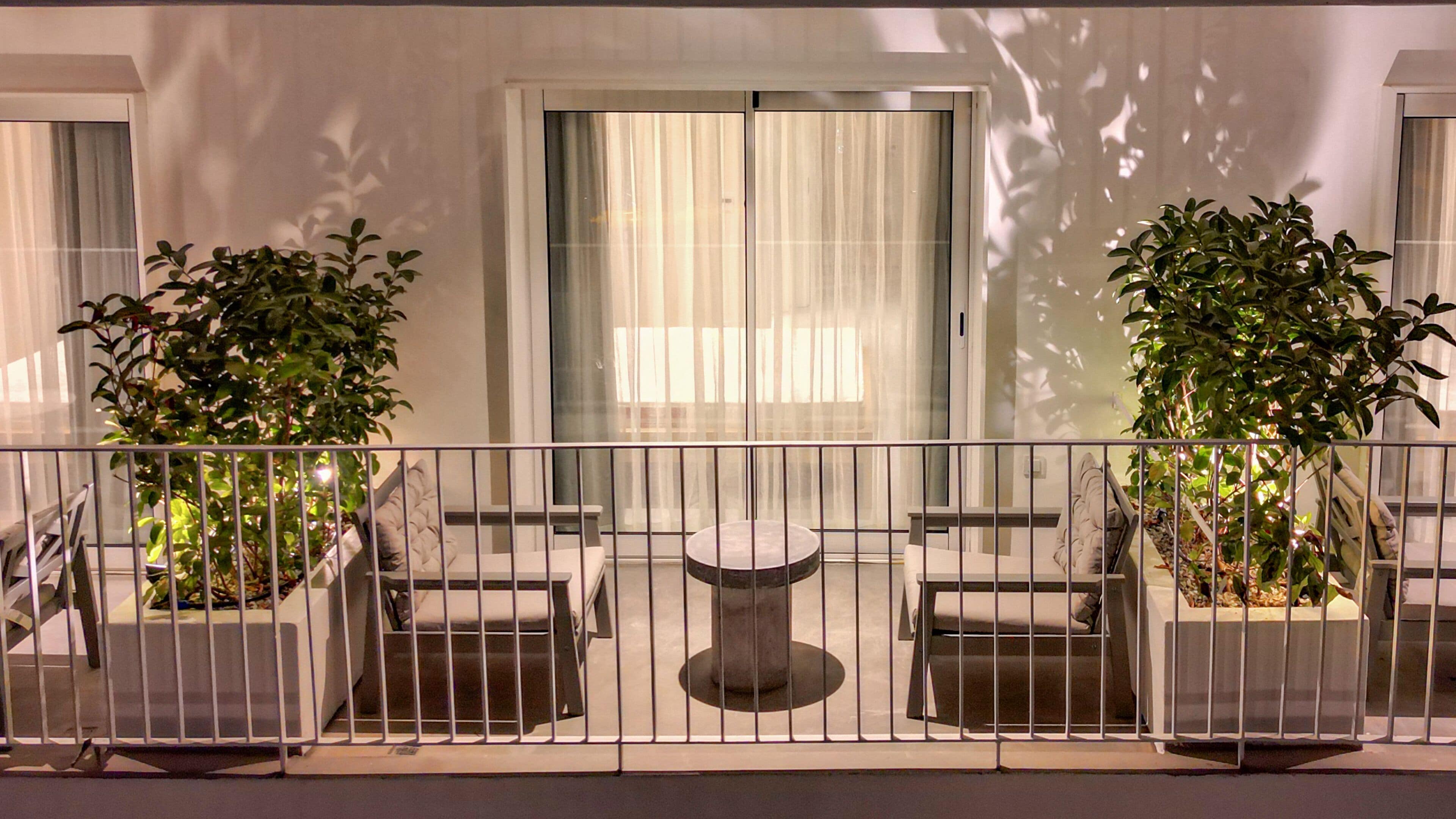 A balcony with a table and two chairs, surrounded by a metal railing.