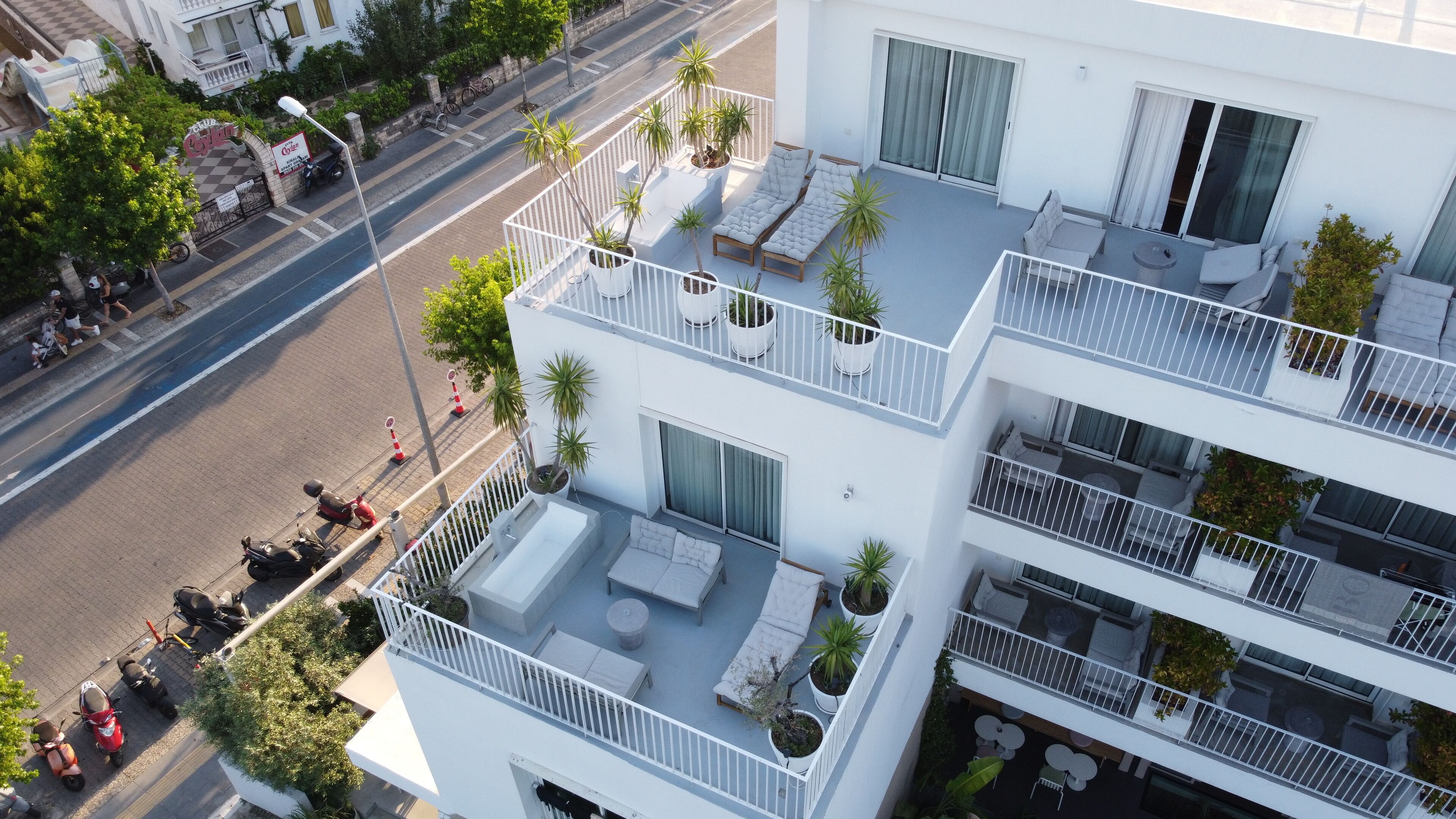 A multi-story building with balconies, outdoor seating areas, and potted plants.