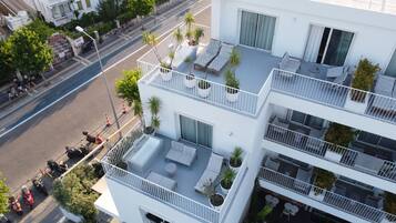 A multi-story building with balconies, outdoor seating areas, and potted plants.