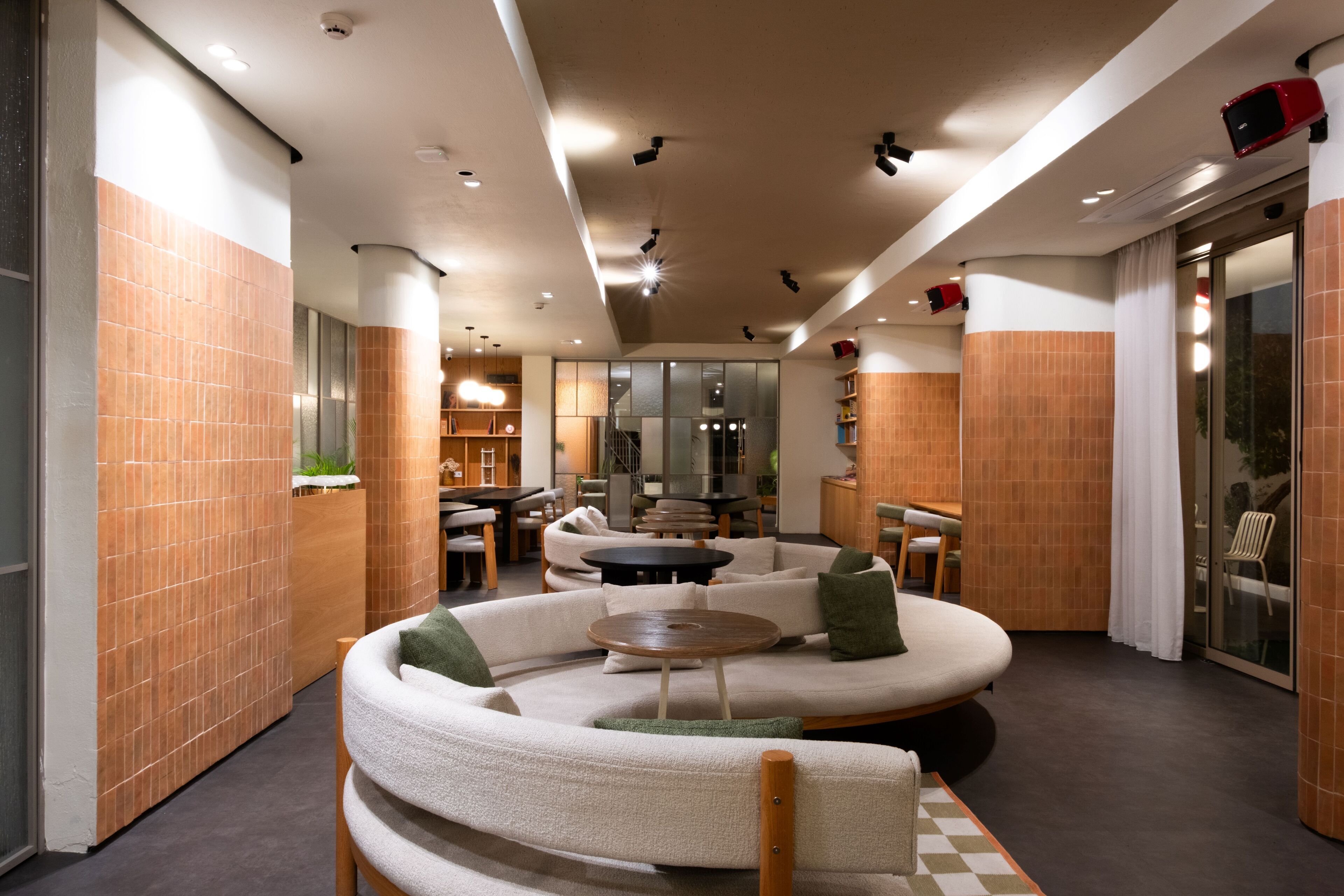 A modern lounge area with a curved seating arrangement, a central round table, and a glass partition.