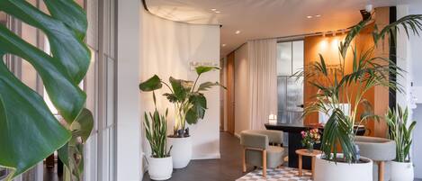 Een moderne hotellobby met potplanten, een geruit tapijt en een zithoek.