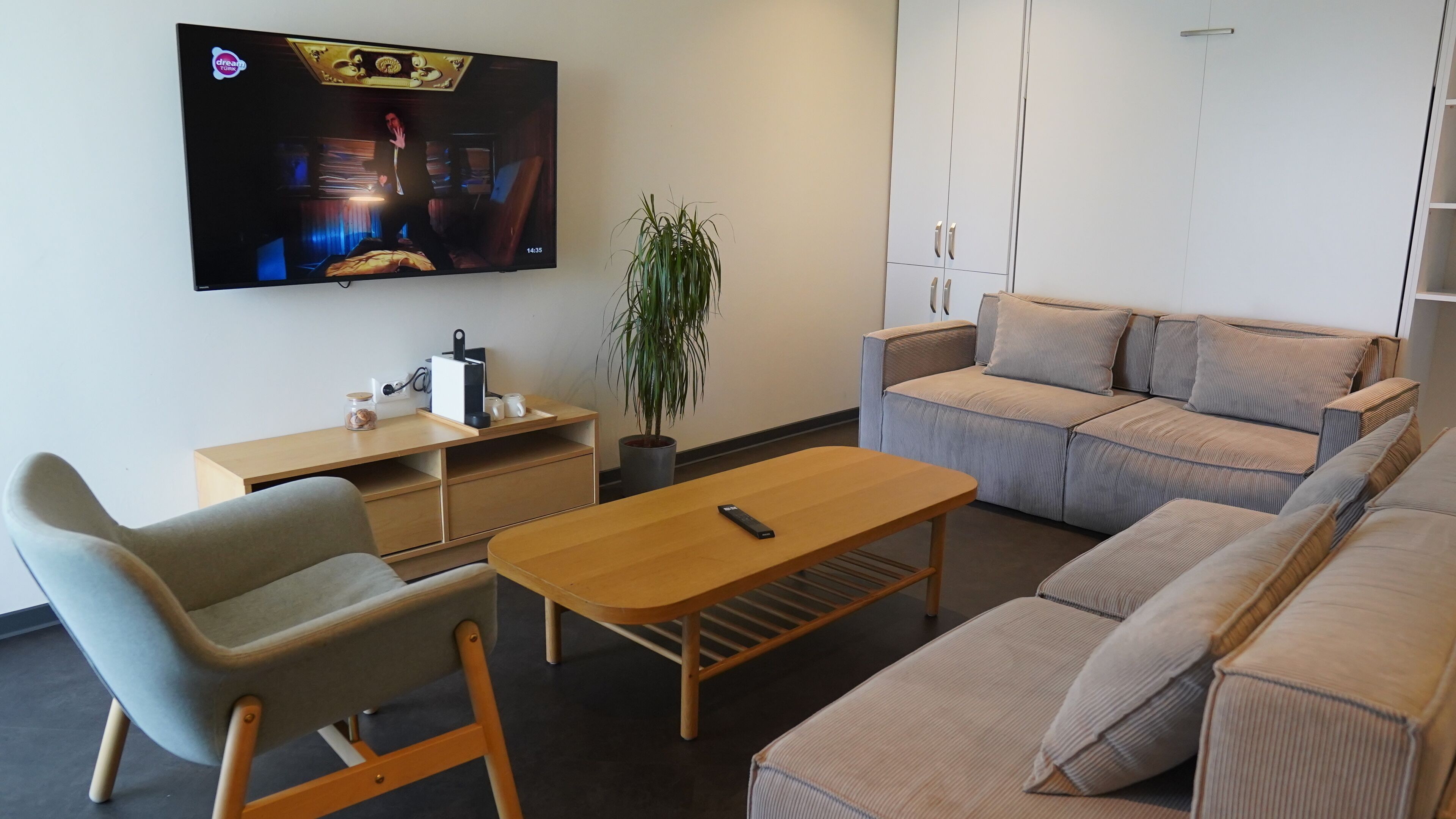 Una sala de estar moderna con televisor, sofá y una mesa de centro de madera.