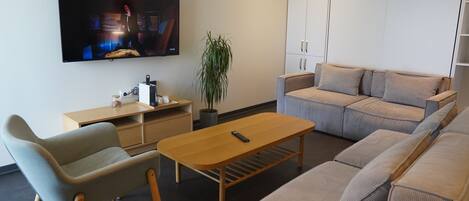 Una sala de estar moderna con televisor, sofá y una mesa de centro de madera.