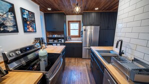 Una cocina moderna con piso de madera, estufa de acero inoxidable, refrigerador y pileta.