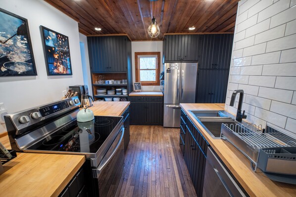 Una cocina moderna con piso de madera, estufa de acero inoxidable, refrigerador y pileta.