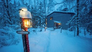 Un sendero cubierto de nieve que lleva a una casa con un letrero que dice 'COZY LOON'.