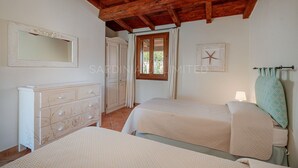 Une chambre avec deux lits, une commode, un miroir, une fenêtre avec des rideaux et une décoration en forme d’étoile de mer sur le mur.