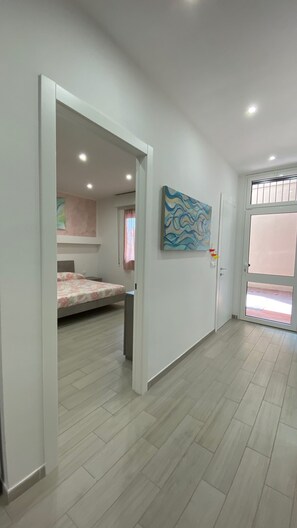 Een kamer met een bed, een schilderij aan de muur en een deur naar een andere kamer.