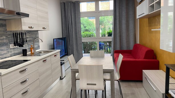 Una cocina moderna con comedor, un sofá rojo y televisor.