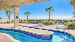 A pool area with blue-tiled edges, lounge chairs, palm trees, and a sign prohibiting diving to play at the pool. - North Shore Villas 806! 3BR/3BA Luxury Condo with Stunning Views! (North Myrtle Beach)