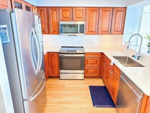 Una cocina con armarios de madera, electrodomésticos de acero inoxidable y un lavamanos doble.