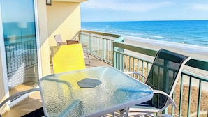 A balcony with a glass table and chairs, overlooking a beach with the ocean. - North Shore Villas 806! 3BR/3BA Luxury Condo with Stunning Views! (North Myrtle Beach)