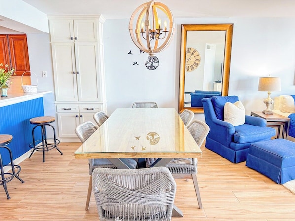 A dining area with a glass-top table surrounded by wicker chairs, a blue sofa, and a blue armchair.