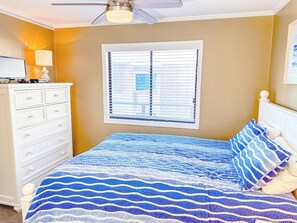 A bedroom with a bed, a dresser, a window with blinds, and a ceiling fan. - Tilghman Beach and Racquet Club 322 (North Myrtle Beach)