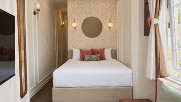 A bedroom with a bed, a round wall mirror, and two wall-mounted lights.
