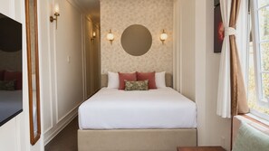 A bedroom with a bed, a round wall mirror, and two wall-mounted lights. - Le Macaron City Center - Boutique Hotel Da Lat (Xuan Huong - Da Lat)