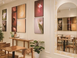 Un espace repas avec des meubles en bois, une plante en pot et des œuvres d’art accrochées aux murs.