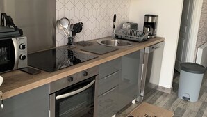 A modern kitchen with grey cabinets, a stainless steel sink, a coffee maker, and a toaster. - Appartement Proche Jonzac (Meux)