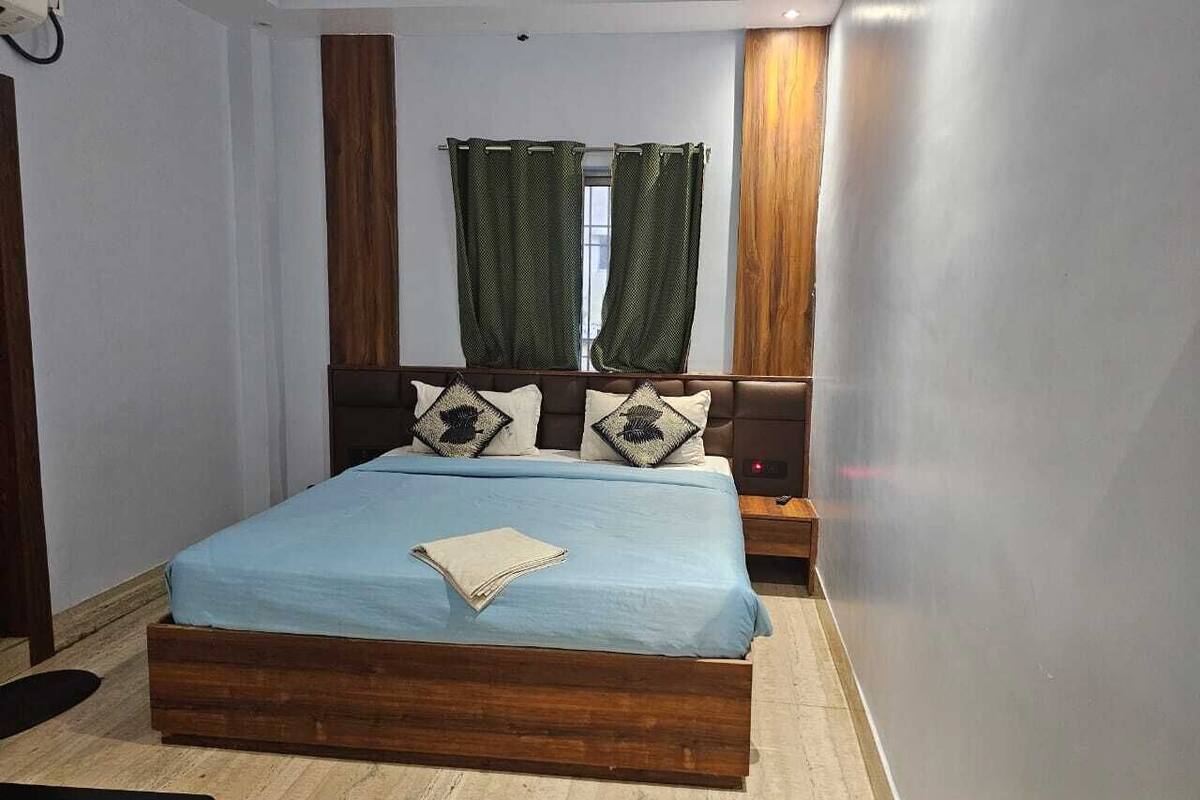 Un dormitorio con una cama de madera, una mesita de noche y una ventana con cortinas.