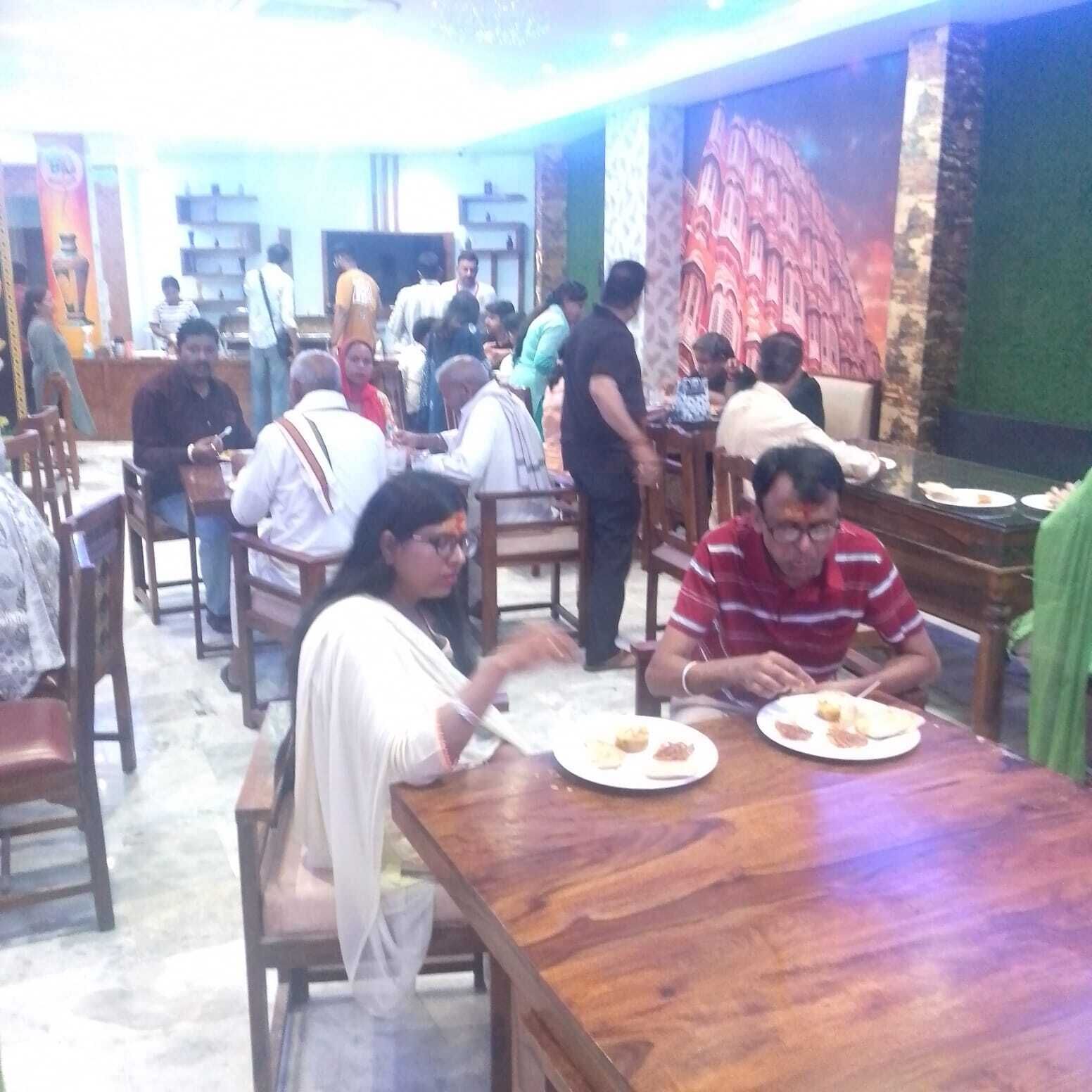 A restaurant with wooden tables and chairs, people dining, and a mural on the wall.