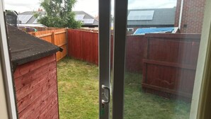 A backyard with a wooden fence, a red shed, and a grassy area. - A wonderful house share: can accommodate up to 15 friends and family.  (Nottingham)