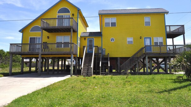 A yellow two-story house with a balcony on the first floor and a staircase leading to the second floor. - Finisterre – Your Topsail Island Escape (North Topsail Beach)