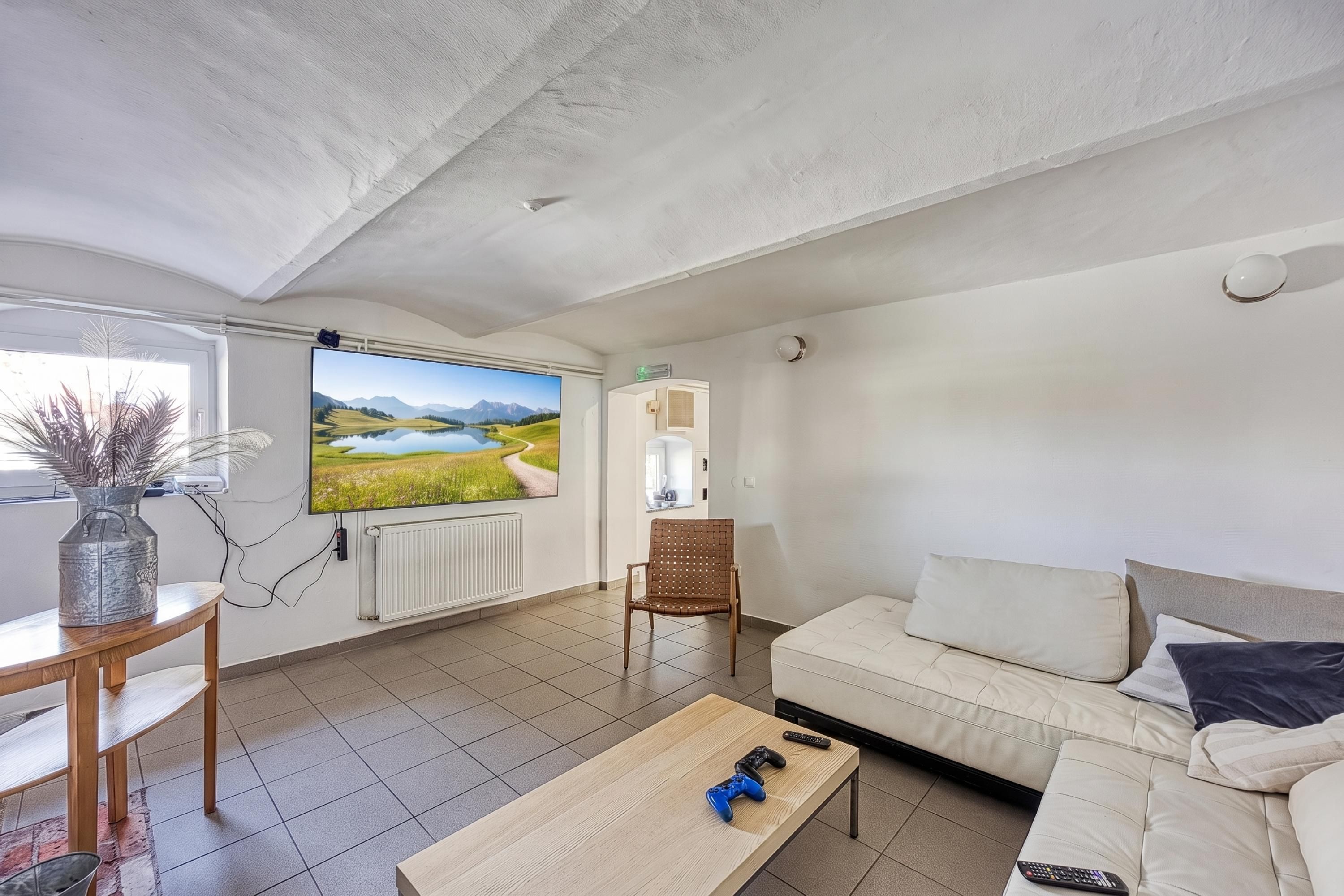 Ein Wohnzimmer mit Fernseher, Sofa, Couchtisch und Sessel.