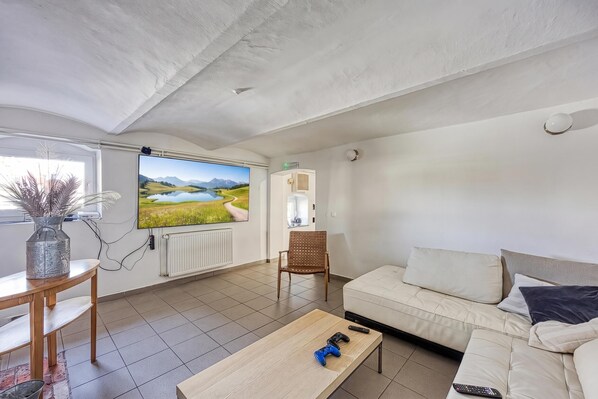 Una sala de estar con televisor, sofá, mesa de centro y sillón.