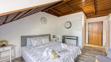 A bedroom with a bed, bedside table, clock, and a door.
