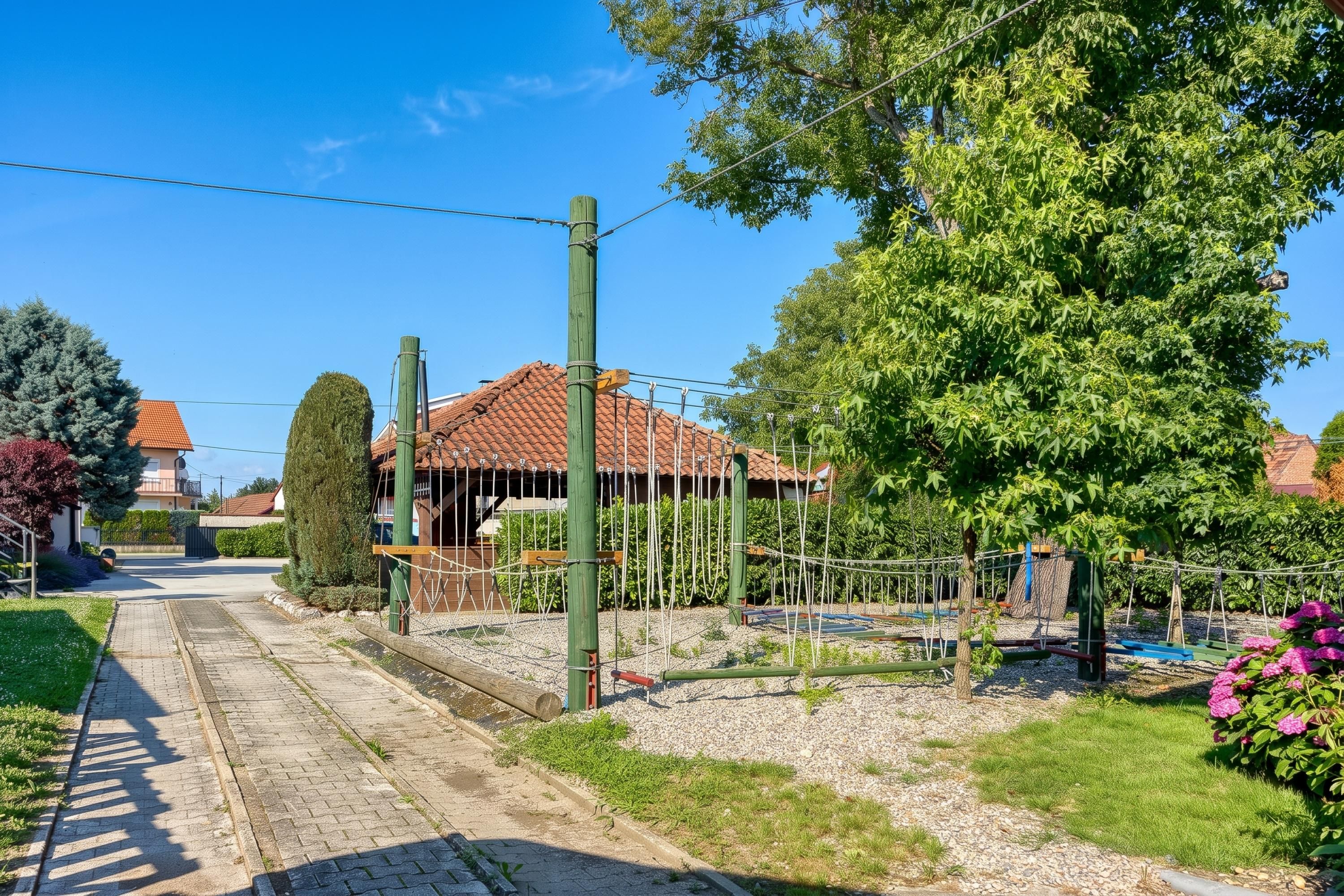 A residential area with a paved road, a wooden fence, and a house with a red-tiled roof.