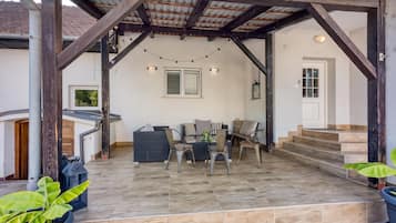 A covered patio area with a table and chairs, a staircase, and potted plants.