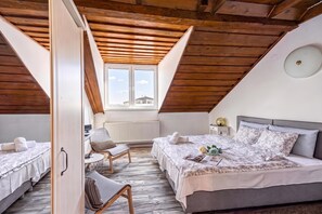 A cozy attic bedroom with a sloped ceiling, two beds, a chair, and a window with a view. - Hedonia Estate /w Sauna and Jacuzzi Near Varazdin (Petrijanec)