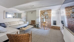 A modern living room with a sofa, chairs, a coffee table, and a brick wall. - Hedonia Estate /w Sauna and Jacuzzi Near Varazdin (Petrijanec)