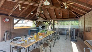 A rustic dining area with a long wooden table, metal chairs, and a ceiling fan. - Hedonia Estate /w Sauna and Jacuzzi Near Varazdin (Petrijanec)