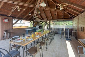 A rustic dining area with a long wooden table, metal chairs, and a ceiling fan. - Hedonia Estate /w Sauna and Jacuzzi Near Varazdin (Petrijanec)