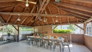 An open-plan dining area with a high wooden ceiling, multiple hanging pendant lights, and a long table set for dining. - Hedonia Estate /w Sauna and Jacuzzi Near Varazdin (Petrijanec)