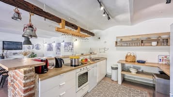 A modern kitchen with a wooden island, built-in appliances, and a rustic ceiling.