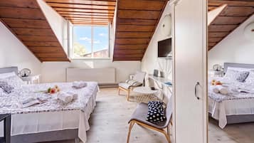 A bedroom with two beds, a desk, a chair, and a wardrobe.