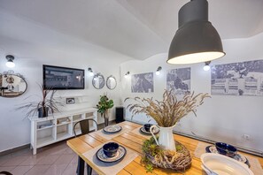 Un comedor con mesa de madera, platos azules y blancos, una jofaina blanca y espejos en la pared.