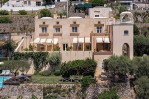 Un edificio de varios pisos con balcones, mobiliario exterior y una zona de piscina.
