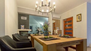 Un comedor con una mesa de madera, sillas negras y una araña.