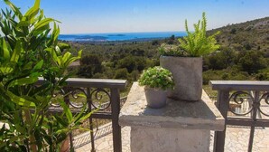 Un balcón con plantas en macetas y vista a un paisaje costero.