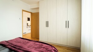 A bedroom with a bed, a wardrobe, and a wooden door leading to a bathroom. - CITYGATE SUNSET BALCONY (Tartu)
