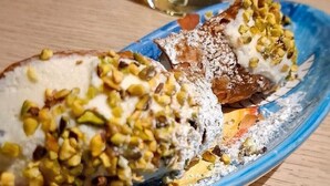 A blue plate with sliced pastries topped with nuts and a white substance. - L'Oasi di Favignana Room and Charme (Favignana)